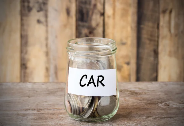 Coins in glass money jar with car label, financial concept.