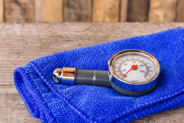 Tire pressure gauge and microfiber cloth on wooden table