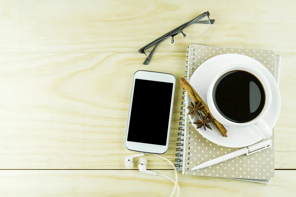 Smart phone, coffee,glasses and book with white pen on wood tabl