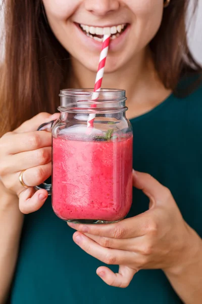 Young woman is holding detox drink, smoothie in glass jar.