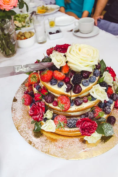 Wedding cake decorated by fruits and flowers.