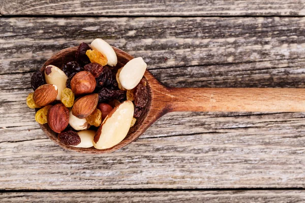 Mixed nuts on a wooden spoon.