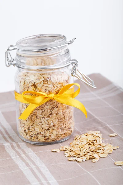 The oat flakes in glass jar and ribbon on towel.
