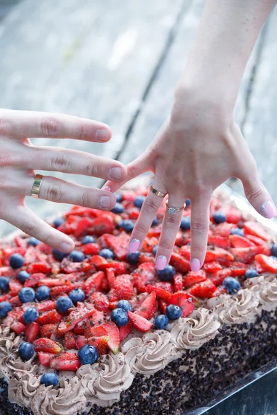 Couple hands with wedding ring and chocolate cake with berries.
