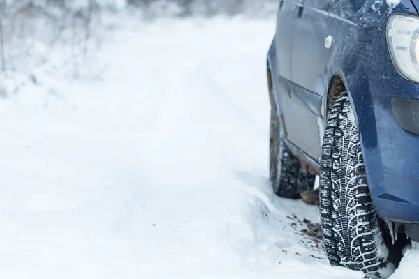 Close up of a cars tires on a snowy road.