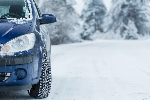 Car on winter road with forest in background.