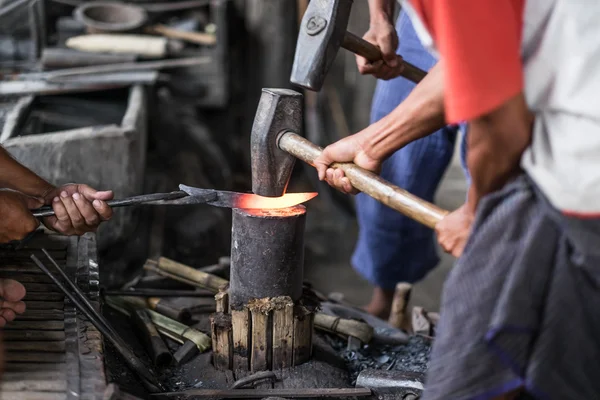 Detail shot of hammer forging hot iron at anvil