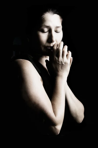 Woman prays on a black background
