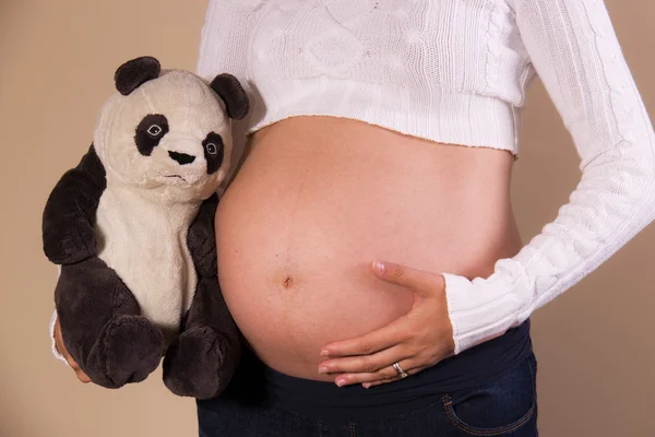 Pregnant woman with stuffed animal showing her belly
