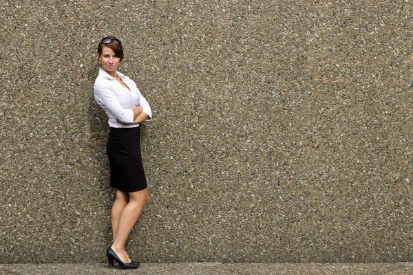Portrait of a young attractive business woman against grey wall