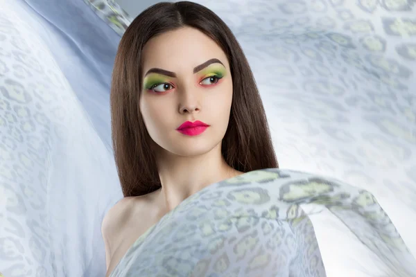 Portrait of a beautiful young woman with bright makeup. A woman surrounded by light flying cloth