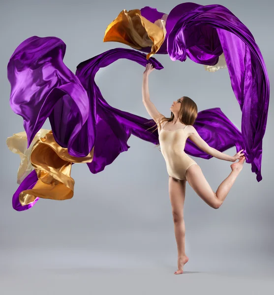 Beautiful young girl dancing. Flowing fabric.