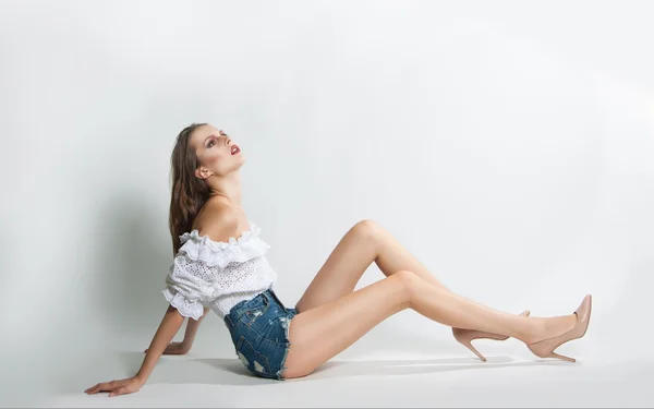 Young beautiful girl in shorts and blouse posing in studio