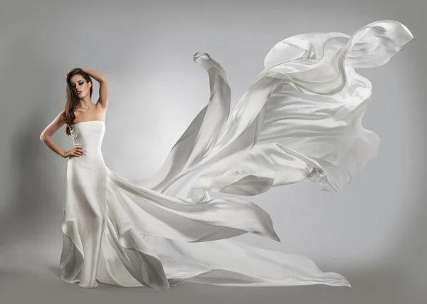 Beautiful young girl in flying white dress. Flowing fabric