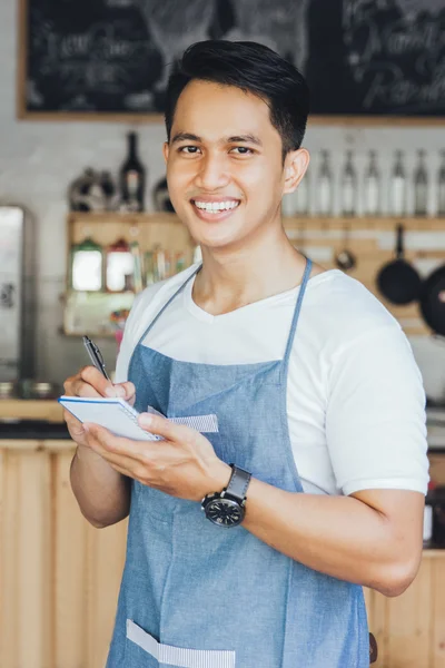 Male waiter in apron writing order