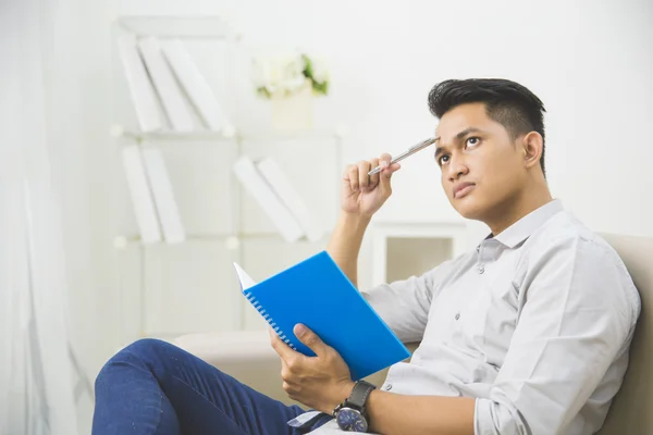 Man thinking while writing on book