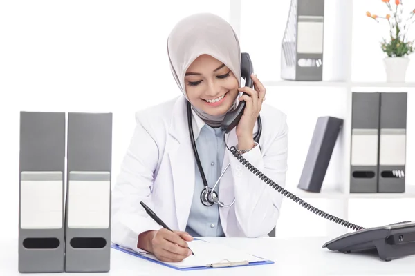 Asian female doctor with stethoscope talking on the phone