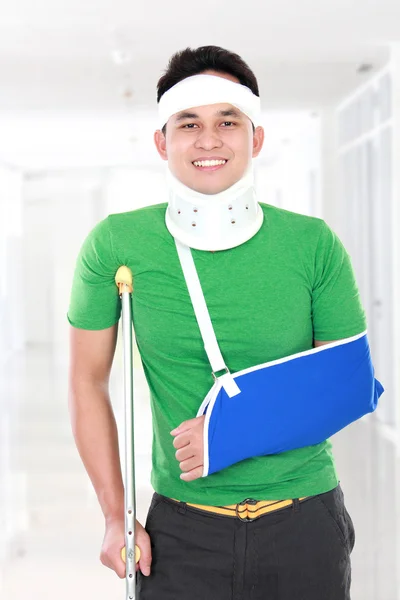 Injured young man use crutch and arm sling