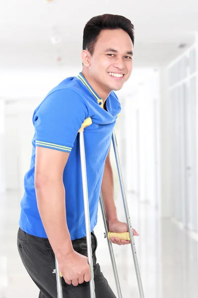 Injured young man walking with the help of crutches