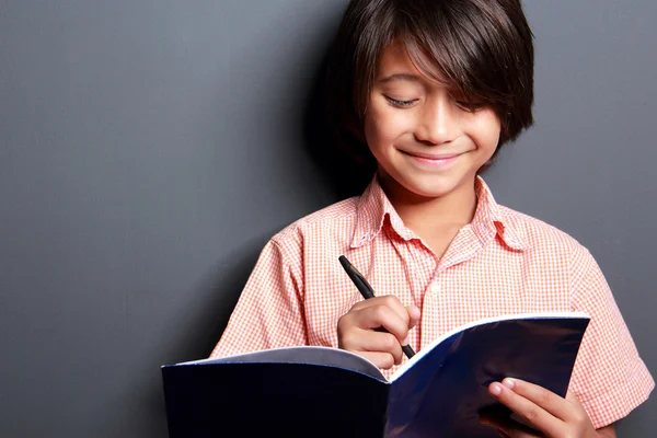 Cute little boy writing on a book