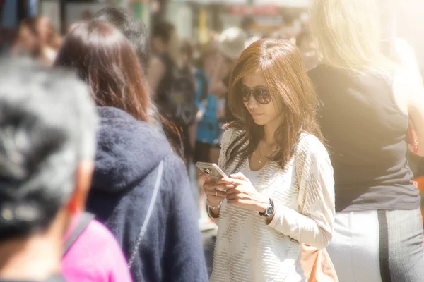 Woman using mobile phone in the crowd