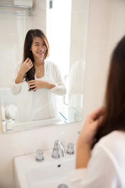 Asian woman posing in front of a mirror, smiling happily
