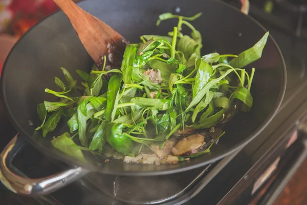 Adding water spinach into burning herb in hotpot, close up