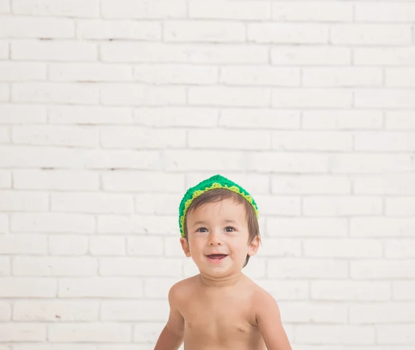 Cute caucasian boy wearing a green knit hat with a bread in fron