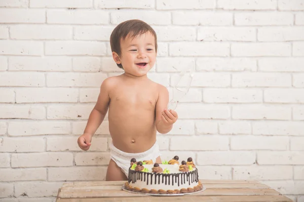 Cute caucasian boy playing with his birthday cake