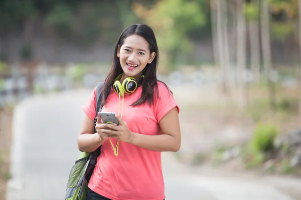 Young Asian student in her outdoor activity, walking while watch