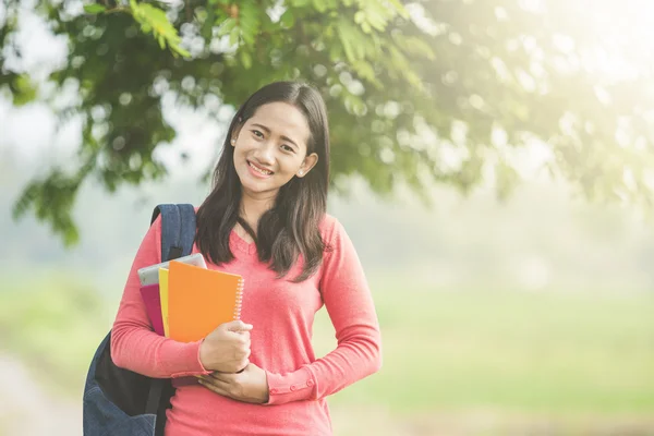 Asian students with books and backpack in the park