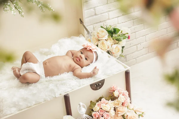 Pretty baby girl feel comfortable lying on crate with fur blanke