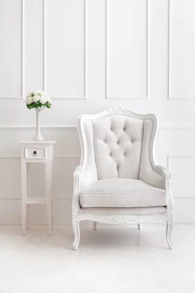 White vintage style armchair and vase of flowers on desk