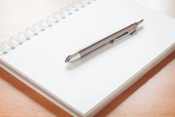 Pen on open blank white notebook on the desk