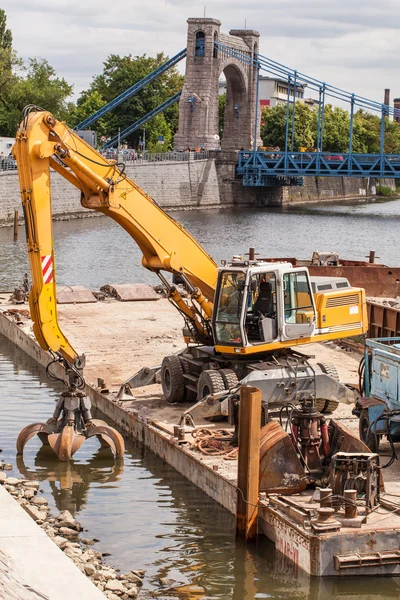 Long arm excavator working on river bank