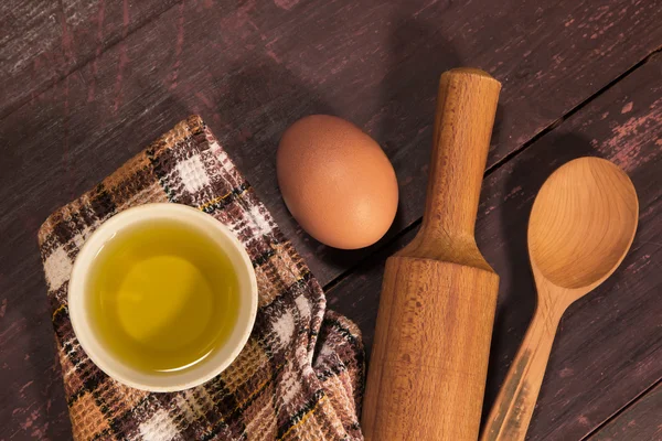 Homemade baking. Kitchen rolling pin, spoon, towel, olive oil, chicken egg on vintage cutting Board