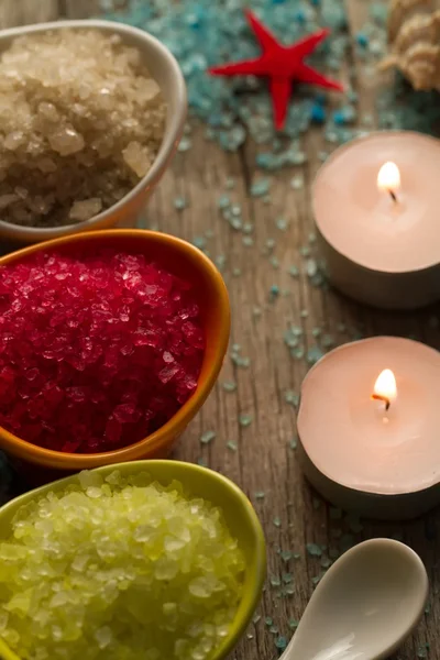 Colorful sea salts and seashells for the bathroom on wooden background. Candles, Spa, aromatherapy.