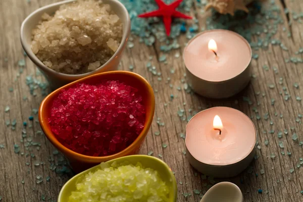 Colorful sea salts and seashells for the bathroom on wooden background. Candles, Spa, aromatherapy.
