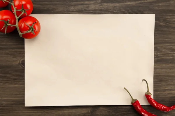 Sheet old vintage paper with tomatoes and Chile peppers aged wooden background. Healthy vegetarian food. Recipe, menu, mock up, cooking.