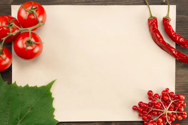 Sheet old vintage paper with berries, tomatoes, chili pepper and grape leaves on wooden background . Healthy vegetarian food. Recipe, menu, mock up, cooking.