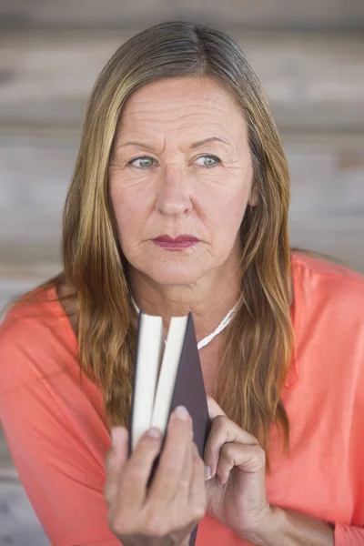Mature woman with book concernd thoughtful