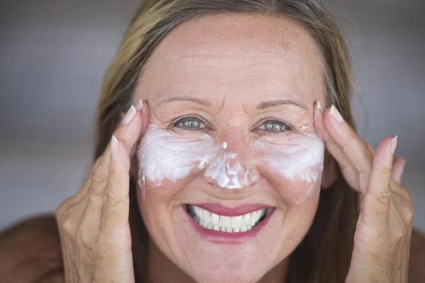 Joyful mature woman face creme skin care