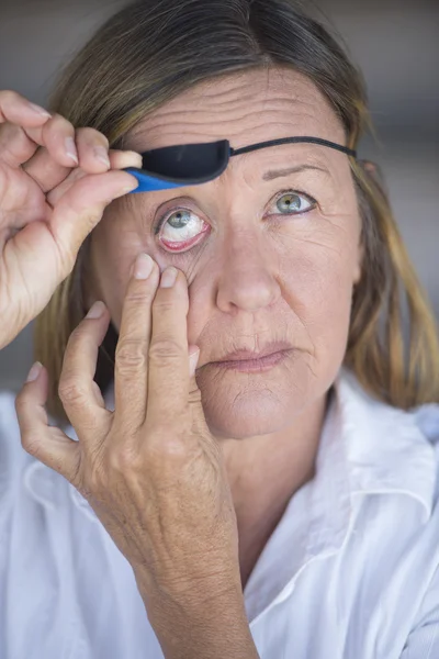 Injured matur woman lifting eye patch protection