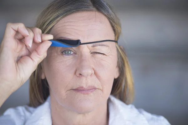 Relaxed woman lifting eye patch portrait