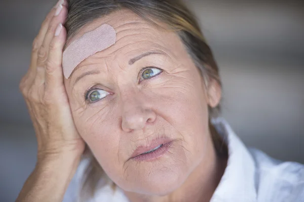 Stressed woman with band aid on forehead
