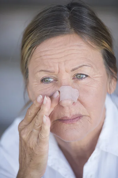 Mature woman with band aid on injured nose