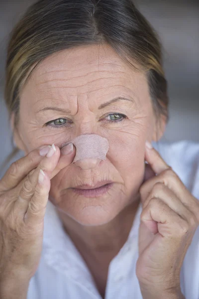 Stressed woman with band aid on injured nose