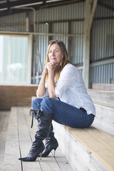 Thoughtful mature woman in jeans and high heels