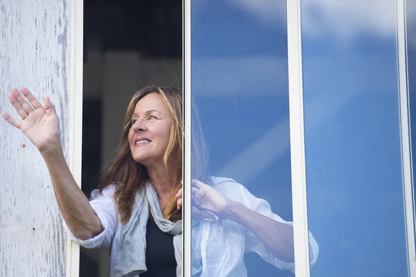 Happy relaxed Woman waving hand at window