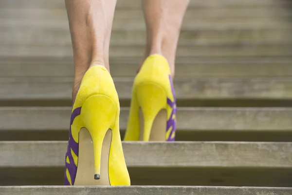 Woman in high heel shoes walking up staircase